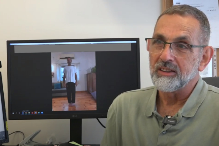 Professor Moshe Frenkel with Ojas Waldman on the screen giving a Zoom qigong class. Photography: Rambam HCC.