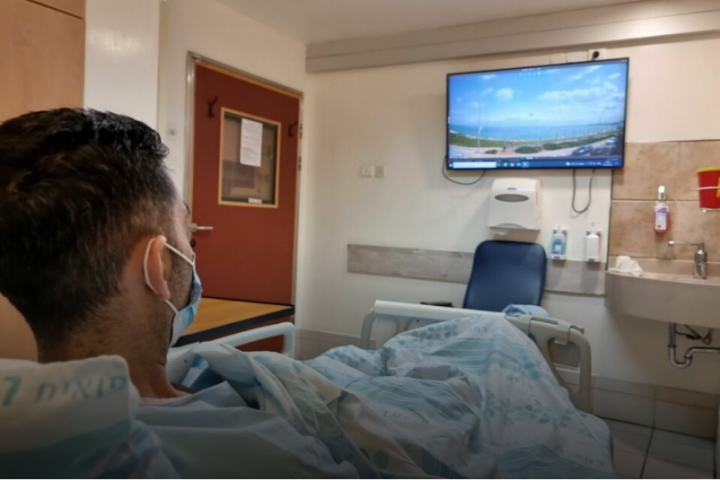 A patient in isolation enjoys the beach view through their virtual window. Photography: Rambam HCC.