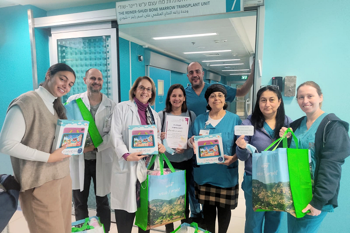 Dr. Shifra Ash (third from left), Ruth Ofir (third from right), and staff members of the Joan & Sanford Weil Division of Pediatric Hematology-Oncology receive the gifts for their pediatric patients. Photography: Rambam HCC.